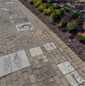 Exterior walkway at the National Corvette Museum featuring engraved tribute bricks of various sizes installed along the landscaped path.